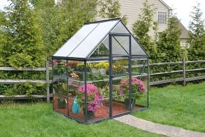 a small, grey greenhouse full of plants