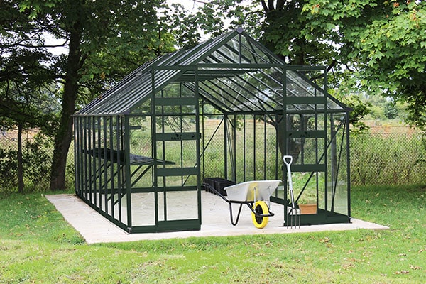 a 10x12 greenhouse with a green aluminium frame and sliding doors
