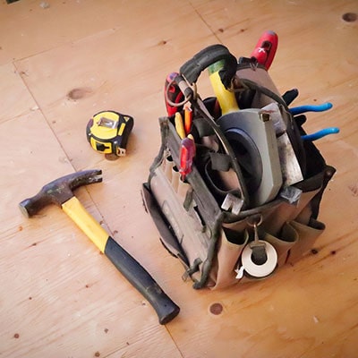 a hammer, measuring tape and tool bag