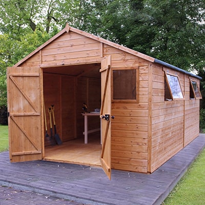 a large wooden shed on a paved shed base
