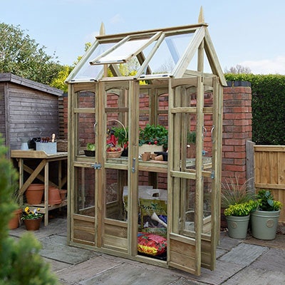 A tall wooden greenhouse with a small footprint