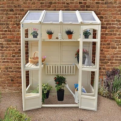 a white lean-to greenhouse with open double doors