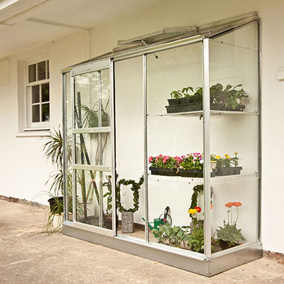 a lean-to greenhouse with a silver frame and open roof vent