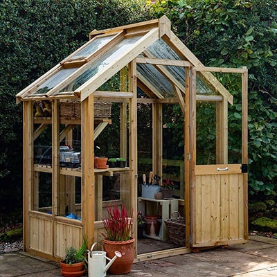 A small wooden greenhouse with a single door