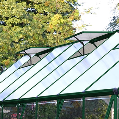 A greenhouse with a green frame and 2 open roof vents