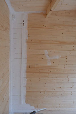white paint being applied to a log cabin's interior