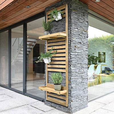 a slatted wooden planter with 2 shelves, attached to the wall of a house
