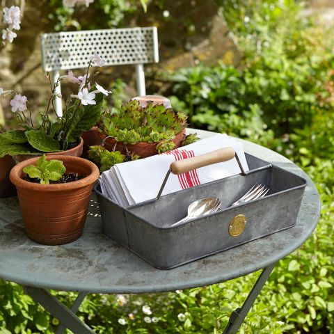 a stylish trug on a table adjacent to some attractive potted plants
