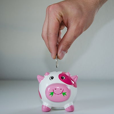 someone putting a coin in a piggy bank