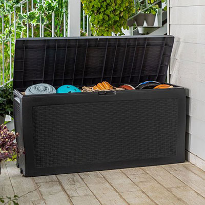 a black plastic patio storage box being used for towel and cushion storage