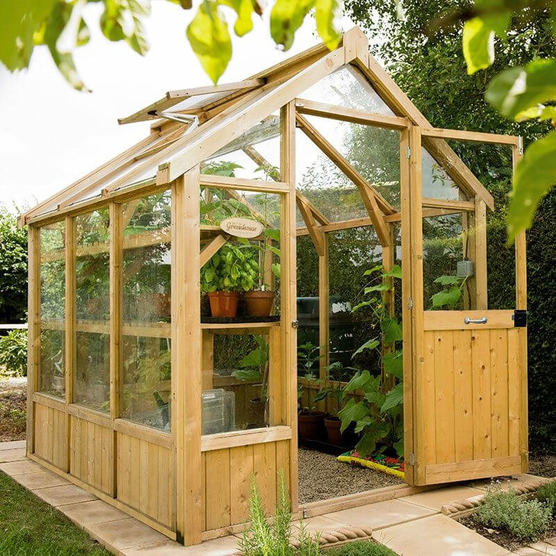 an image of a wooden greenhouse filled with plants