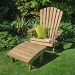 A green cushion and a book resting on top of the Forest Saratoga Wooden Garden Chair, which is situated on a lawn.
