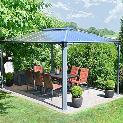 A table and chairs underneath a grey polycarbonate gazebo, overlooking countryside