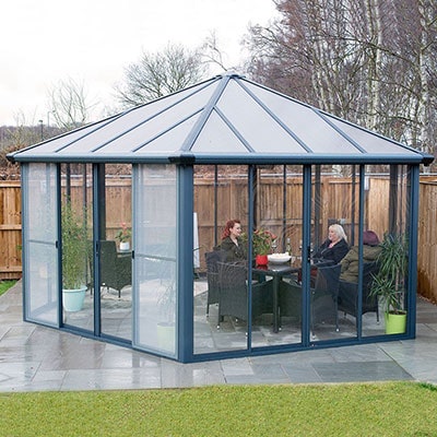 3 people sat down inside a large polycarbonate gazebo, with glass sides