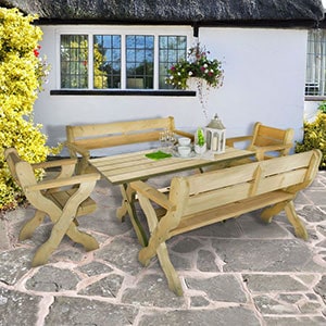 The Forest Grizedale 8 Seater Wooden Garden Table and Chairs Dining Set, situated outside a white, thatched cottage.