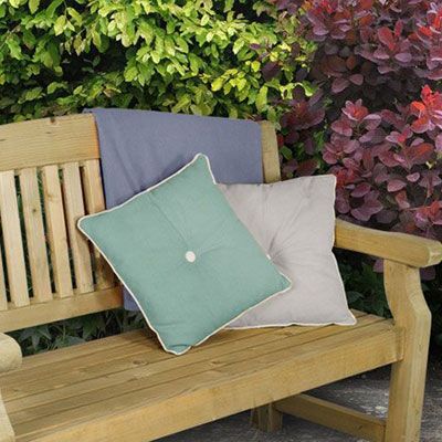 2 garden cushions and a throw on a wooden garden bench
