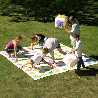 children playing a garden twister game and 2 people holding giant, inflatable dice