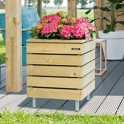 A square wooden container on legs, containing pink flowers