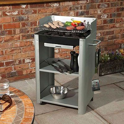 a stainless steel BBQ with food on the grill and tools on the 2 shelves