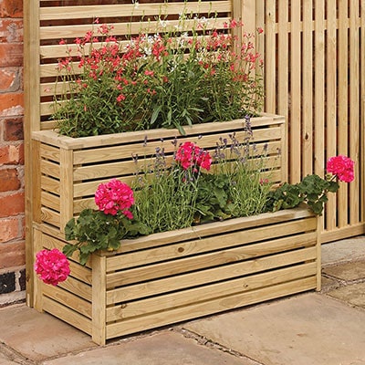 A 2-tiered wooden planter with deep pink flowers inside